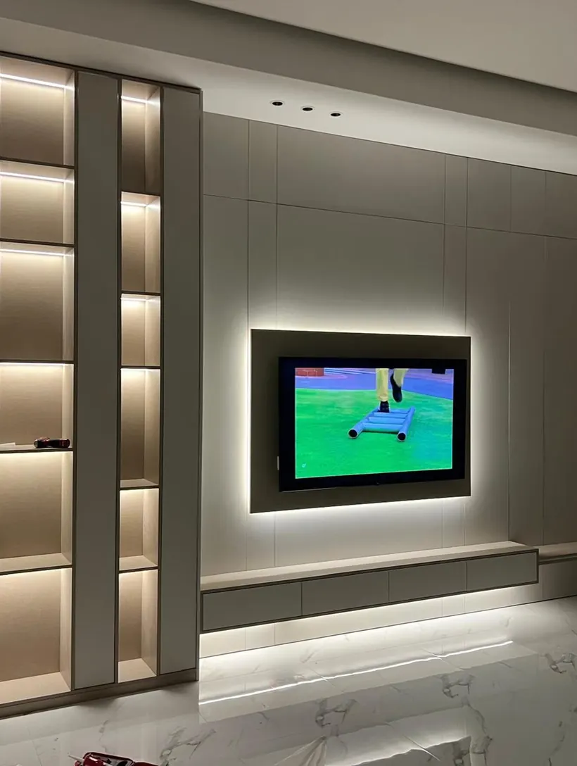 Installed media wall with backlit TV panel and grey lacquer